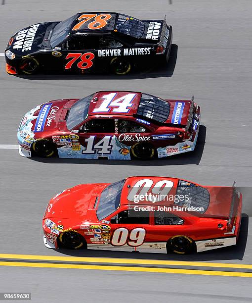 Regan Smith, driver of the Furniture Row Racing Chevrolet, races Tony Stewart, driver of the Olds Spice Matterhorn Chevrolet, and Mike Bliss, driver...