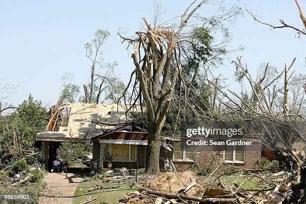 Homeowners sit under a car port waiting for relief to arrive on April 25, 2010 in Yazoo City, Mississippi. On Saturday a massive tornado hit the...
