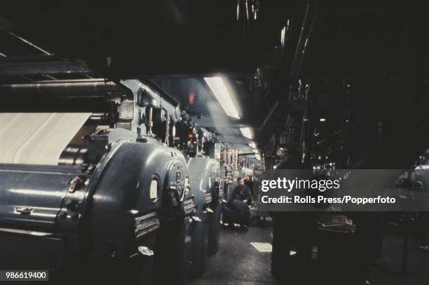 View of workers operating giant printing presses in the machine room of the Daily Mirror newspaper, located in the basement of the Daily Mirror...