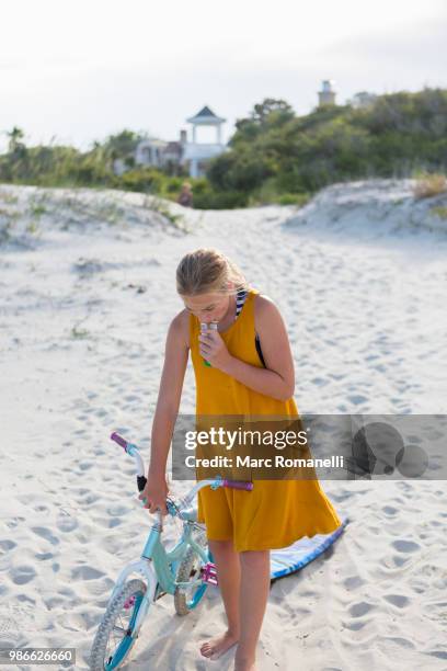 girl walking small bike on the beach - marc romanelli stock pictures, royalty-free photos & images