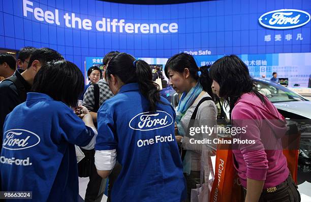 Staff members of Changan Ford introduce car to visitors during the Beijing Auto Show on April 25, 2010 in Beijing of China. Major global automakers...