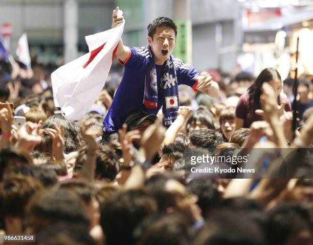 People celebrate Japan's qualification for the World Cup round of 16 in Tokyo's Shibuya entertainment district in the early hours of June 29, 2018....