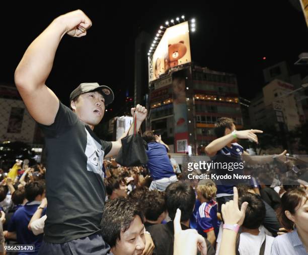 People celebrate Japan's qualification for the World Cup round of 16 in Tokyo's Shibuya entertainment district in the early hours of June 29, 2018....