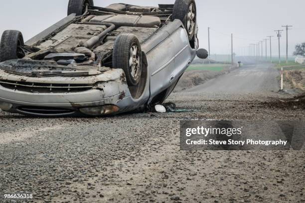 an overturned car on a rural road. - verkeersongeluk stockfoto's en -beelden