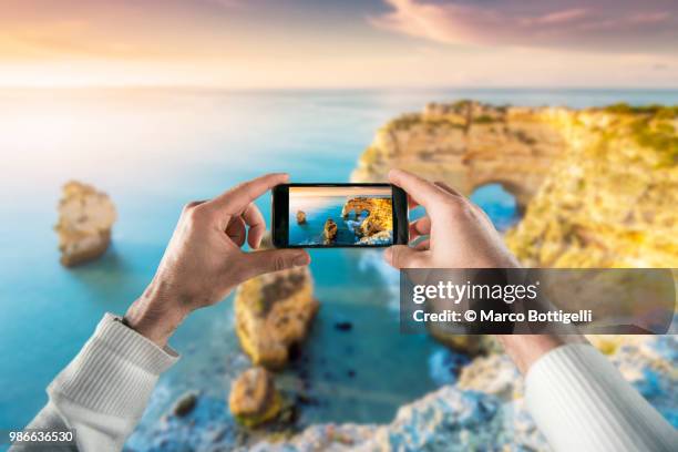 tourist taking picture with smartphone at praia de marinha, portugal. personal perspective view. - marinha foto e immagini stock