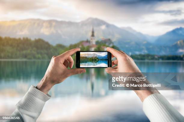 tourist taking picture with smartphone at bled lake, slovenia. personal perspective view. - bled slovenia stock pictures, royalty-free photos & images