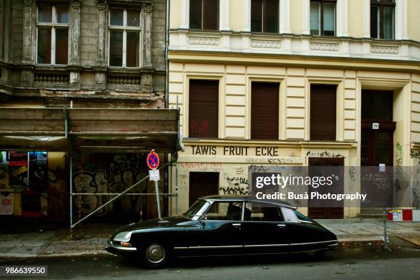 an old citroen ds pallas parked in front of old apartment buildings in the district of prenzlauerberg, berlin, germany - citroën ds - fotografias e filmes do acervo