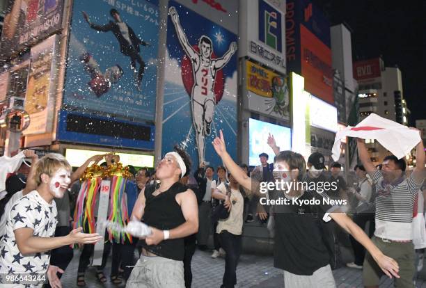 People celebrate Japan's qualification for the World Cup round of 16 in Osaka's Minami district in the early hours of June 29, 2018. Japan advanced...