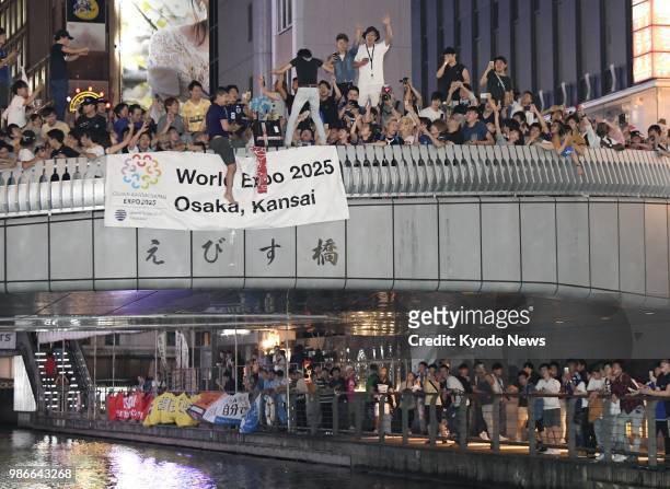 The Ebisu Bridge in Osaka's Minami is packed with people celebrating Japan's qualification for the World Cup round of 16 in the early hours of June...