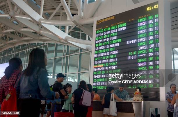 Travellers check their flights at Ngurah Rai airport in Denpasar, Bali which is closed on June 29, 2018 after a pilot report detected volcanic ash as...