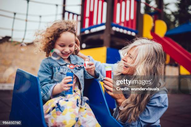 amor de abuela y pequeña nieta que sopla burbujas juntos en el patio - great granddaughter fotografías e imágenes de stock