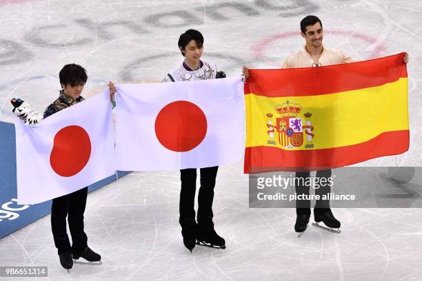 Olympic champion Yuzuru Hanyu and second-placed Shoma Uno from Japan and third-placed Javier Fernandez from Spain holding their countries' flags in...