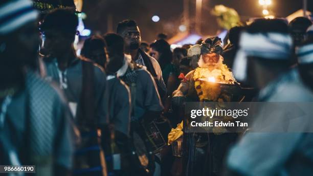 an old indian male prayer lighting up a candle and getting ready to walk toward batu cave hindu temple during the night of thaipusam in malaysia - monkey god stock pictures, royalty-free photos & images