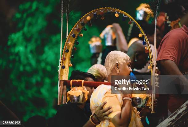 a female indian hindu prayer carry a religious equipment climbing up to batu cave hindu temple worshipping the god during the night of thaipusam in malaysia - traditional piercings stock pictures, royalty-free photos & images