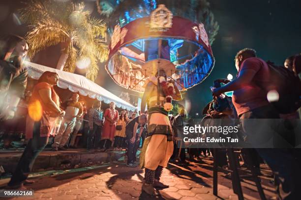 a prayer who pierced himself and carry the statue of god heading to batu cave temple at the night of thaipusam  in malaysia with other thousand of prayers - traditional piercings stock pictures, royalty-free photos & images