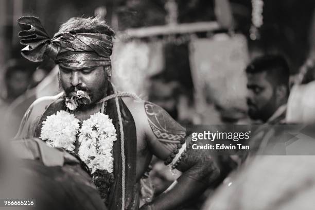 a black and white image of a hindu indian male prayer with smoking cigar getting himself ready before heading toward batu cave temple during the night of thaipusam in malaysia - batu caves stock pictures, royalty-free photos & images