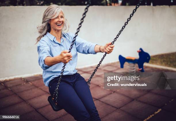 glückliche senior frau sitzen auf schaukel und ruhestand genießen - woman on swing stock-fotos und bilder