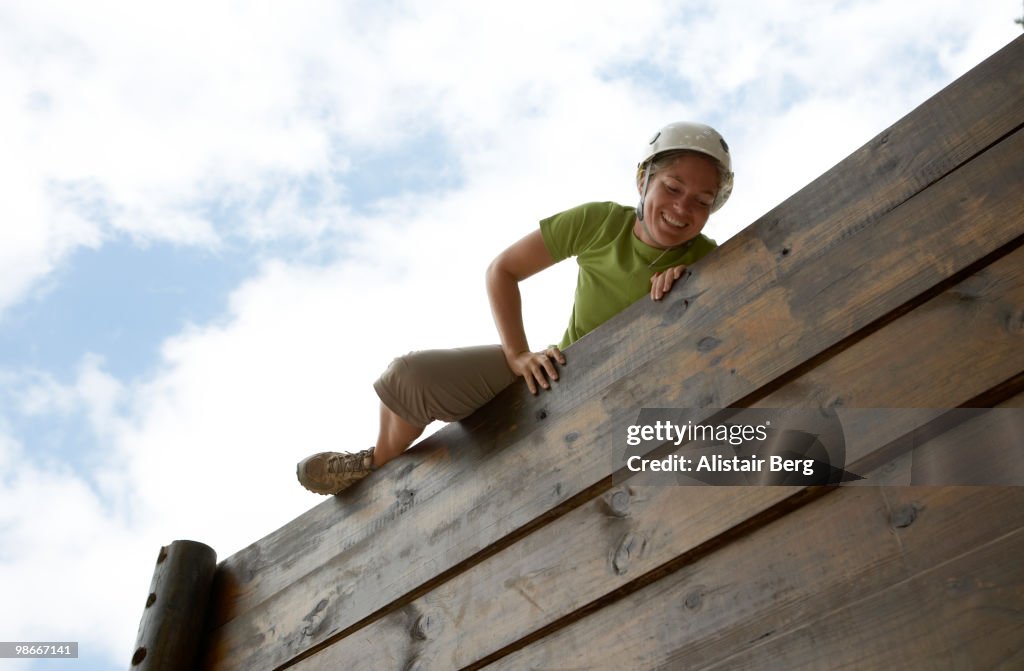 Woman climbing over obstacle course