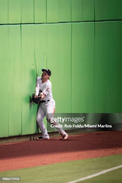 Derek Dietrich of the Miami Marlins collides with the wall while attempting to catch a ball in foul territory during the game against the Arizona...