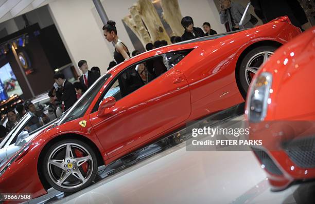 Model poses next to a Ferrari 458 Italia on display at the Beijing Auto Show near the capital's airport on April 26, 2010. Luxury car sales in China...