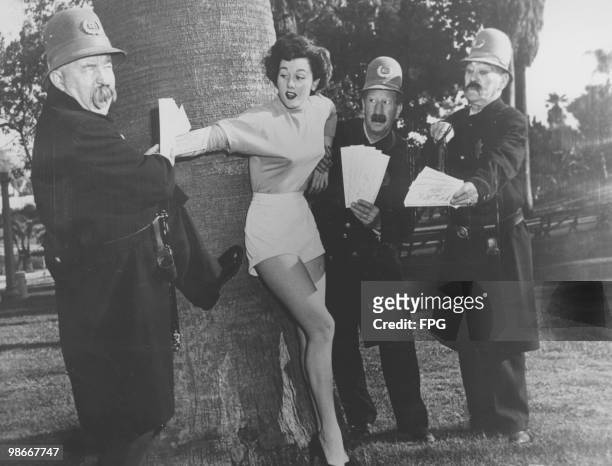 Three 'Keystone Kops' try to sell Policeman's Ball tickets to model Wendy Waldron in MacArthur Park, Los Angeles, USA, 20th June 1950. The 'Kops' are...