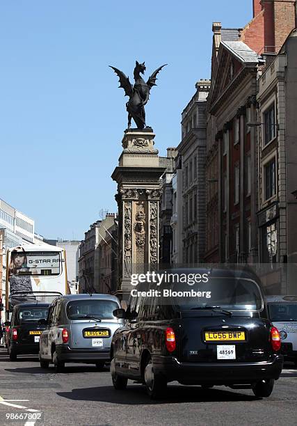 Traffic passes a statue of a Griffin carrying the coat of arms of the City of London, as it stands on a pedestal in London, U.K., on Friday, April...