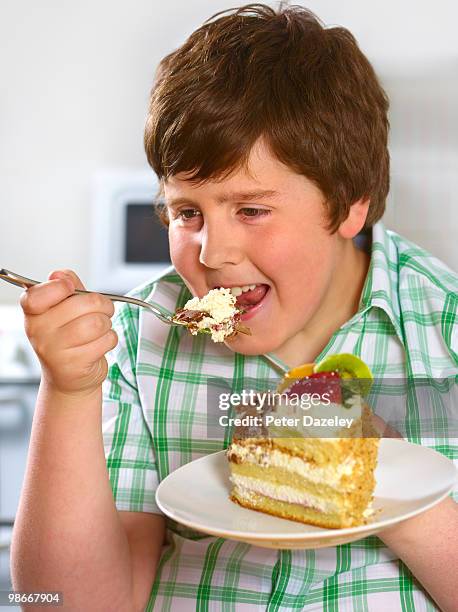overweight boy eating gateaux  - transfettsäure stock-fotos und bilder