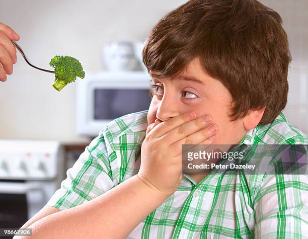 overweight boy hates broccoli - childhood obesity stock pictures, royalty-free photos & images