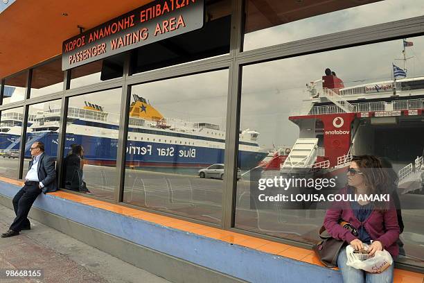 People sit by empty passender waiting area by moored ferries at the port of Piraeus near Athens on April 26, 2010 as seamen stage a 24-hour strike to...