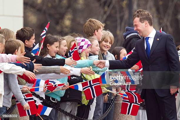 Russian President Dmitry Medvedev shakes hands with a young Norwegian girl as he is welcome by Norwegian King Harald , and school children outside...