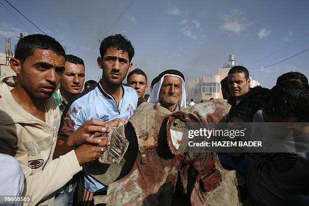 Palestinian mourners display the blood stained flak jacket of killed Hamas official Ali Suweiti, during his funeral in the West Bank village of Beit...