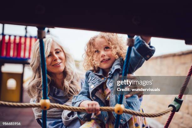 grandmother helping granddaughter climb rope ladder at playground jungle gym - great granddaughter stock pictures, royalty-free photos & images