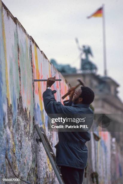 Un jeune homme détruit le Mur de Berlin à l'aide d'un marteau et d'un burin le 22 février 1990.