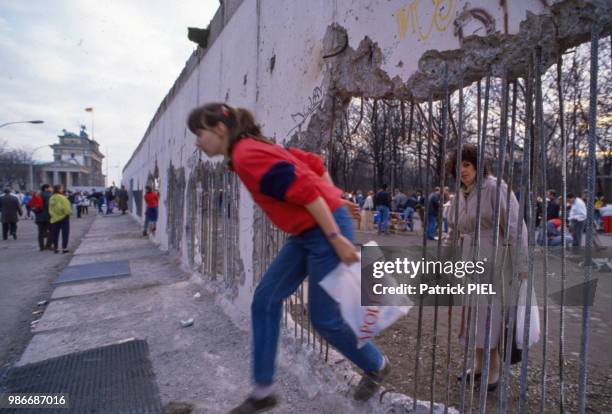 Une jeune allemande passe dans un trou du Mur près de la Porte de Brandebourg à Berlin le 20 février 1990, Allemagne.