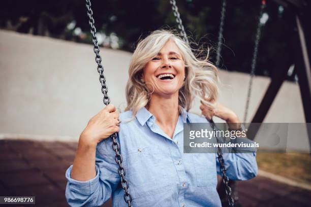 retrato de mujer madura con pelo gris sentado en columpio - mujer feliz fotografías e imágenes de stock