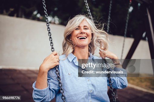Portrait of mature woman with gray hair sitting on swing Portrait of mature woman with gray hair sitting on swing