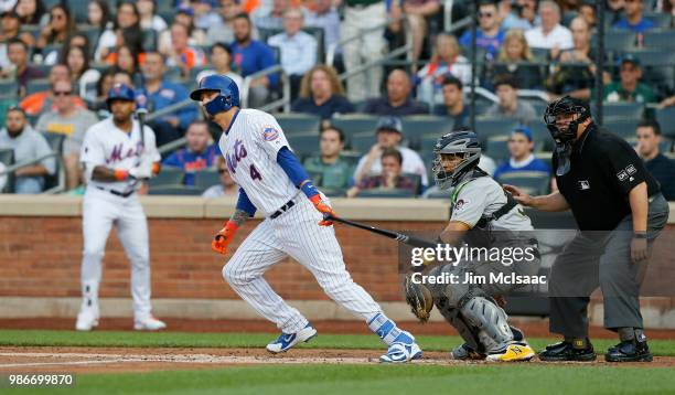 Wilmer Flores of the New York Mets fiollows through on a first inning two run single against the Pittsburgh Pirates at Citi Field on June 26, 2018 in...