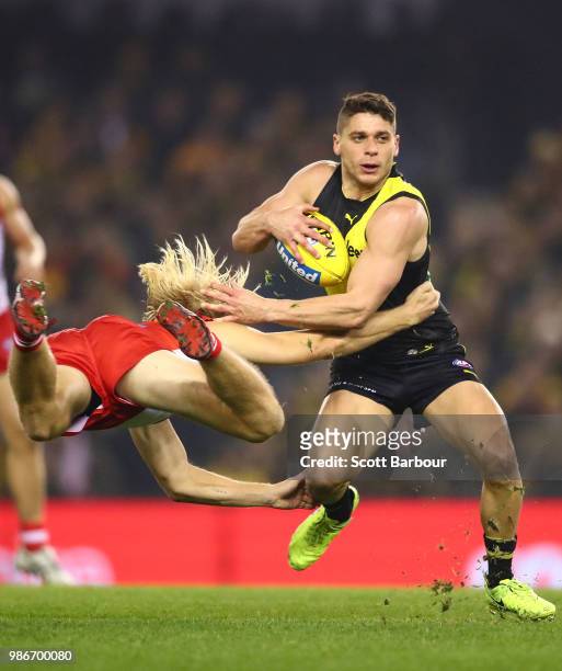 Dion Prestia of the Tigers is tackled by Harry Cunningham of the Swans during the round 15 AFL match between the Richmond Tigers and the Sydney Swans...