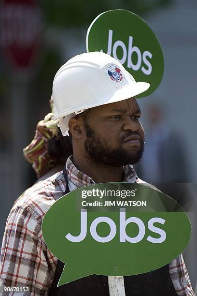 An activist holds a placard calling for more jobs as he participates in a street theater with activists dressed as bankers attempting to win a...