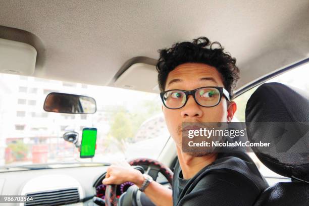 young asian intellectual male driver looking back inside car - man looking back stock pictures, royalty-free photos & images