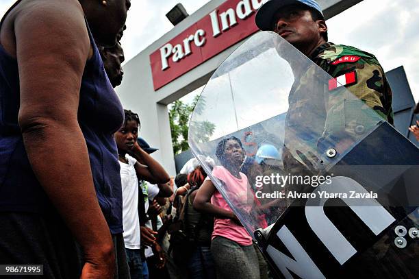 Woman cries, having been hit, as a MINUSTAH security personnel member stands guard as people try to force their way into the warehouse of the...