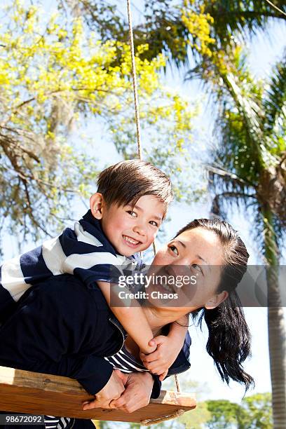 mom and son on a wooden swing - newoutdoors stock pictures, royalty-free photos & images