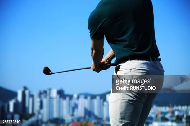 man swinging golf club, rear view - adventure club stockfoto's en -beelden