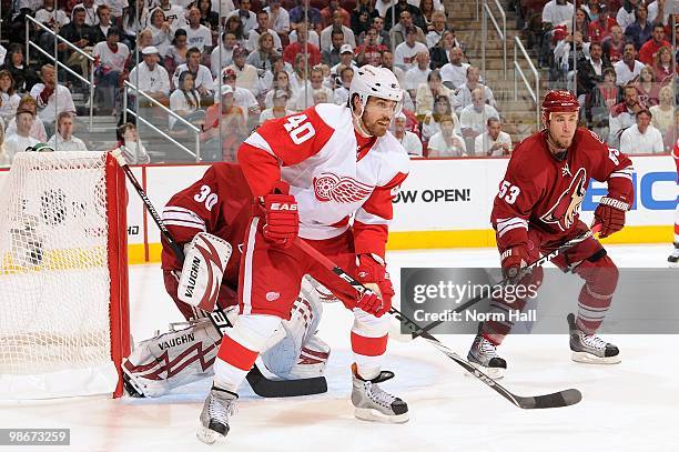 Henrik Zetterberg of the Detroit Red Wings and Derek Morris of the Phoenix Coyotes look for the puck while standing in front of the Coyotes net in...