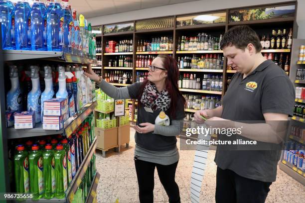 Febuary 2018, Germany, Rostock: Nadine Berninger, branch manager of the Cap Markt in the Seidelstrasse, applies pricetags to goods with Benjamin...