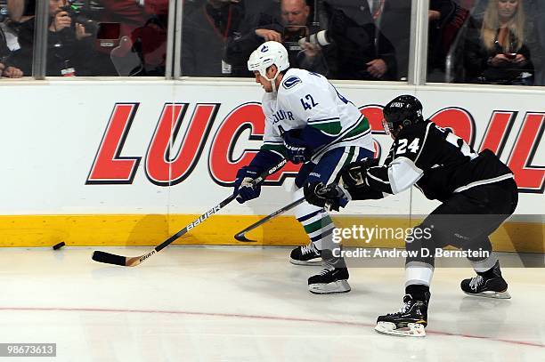 Kyle Wellwood of the Vancouver Canucks skates with the puck against Alexander Frolov of the Los Angeles Kings in Game Four of the Western Conference...