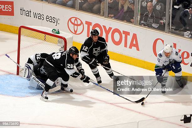 Kyle Wellwood of the Vancouver Canucks reaches for the puck against Jarret Stoll and Randy Jones of the Los Angeles Kings in Game Four of the Western...