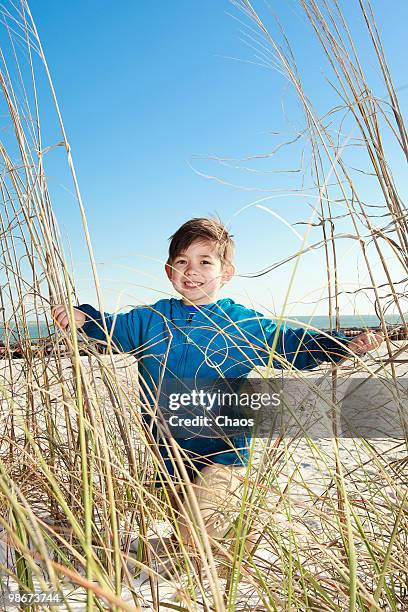 boy walking through beachgrass and sand dunes - newoutdoors stock pictures, royalty-free photos & images
