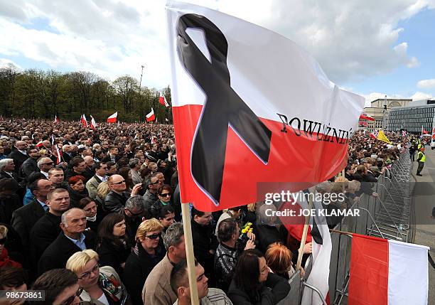 Polish flag flies as people attend a mass during a public memorial service held on Pilsudski square in Warsaw on April 17, 2010 for the 96 victims of...