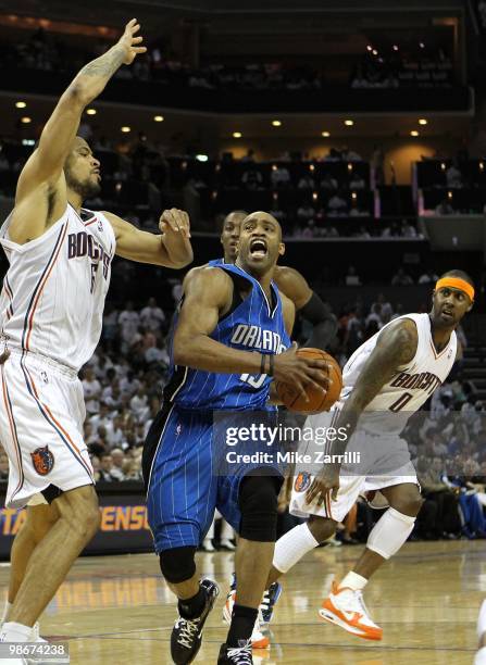 Forward Vince Carter of the Orlando Magic drives in the lane while Tyson Chandler of the Charlotte Bobcats defends him and Bobcats forward Larry...